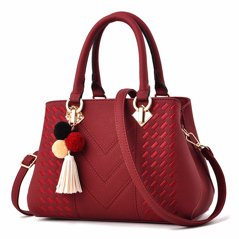Elegante Damenhandtasche in Rot mit Quasten-Anhänger und goldfarbenem Metallverschluss.