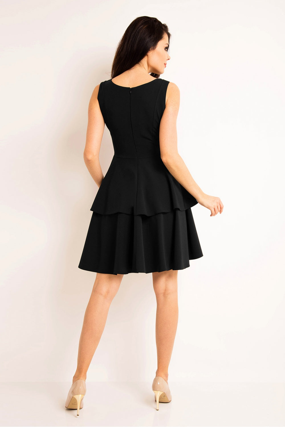 Woman wearing black sleeveless tiered daydress model 80496 with back zipper and nude heels