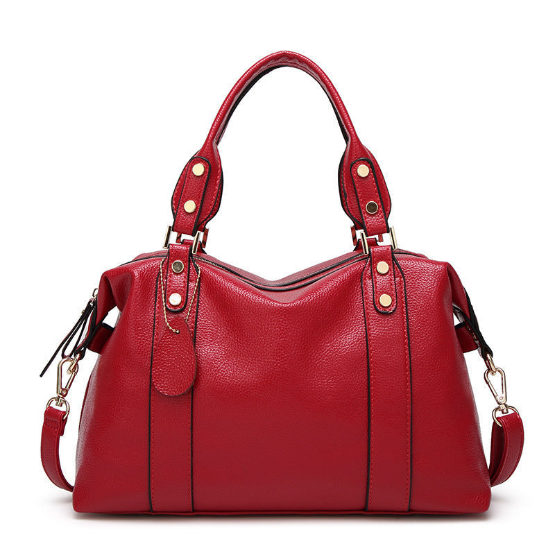 Moderne Damenhandtasche in Weinrot mit strukturierter Oberfläche, goldfarbenen Detail und verstellbarem Schulterriemen - Vorderansicht